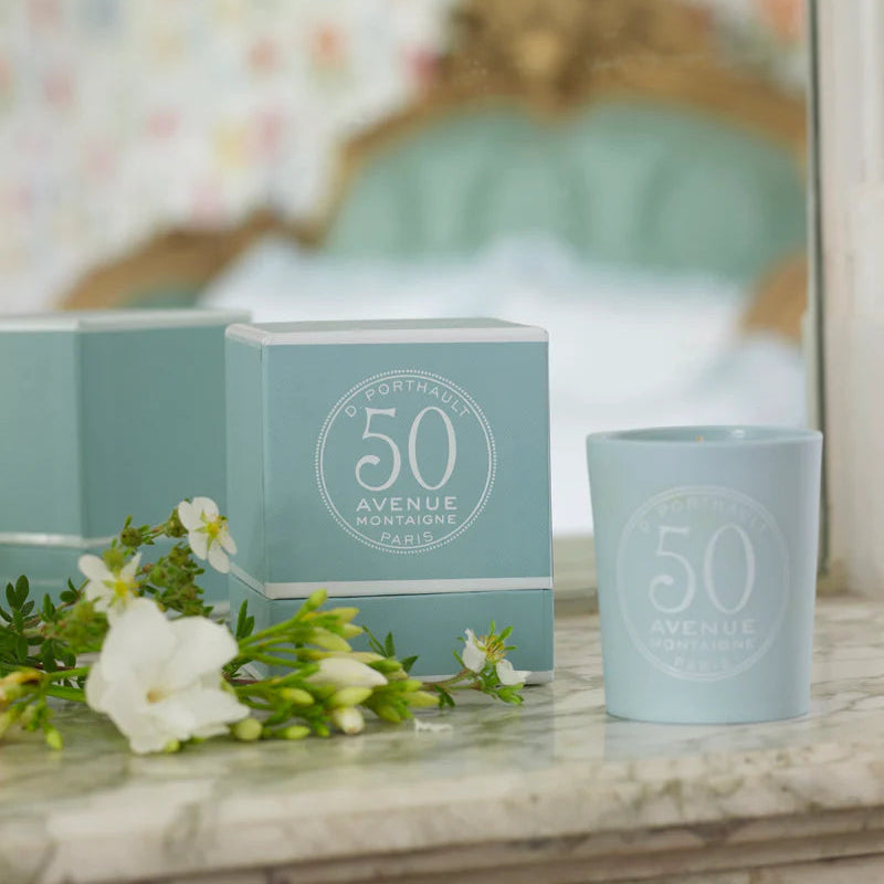 Light blue candle and packaging with '50 Avenue' branding on a marble surface.