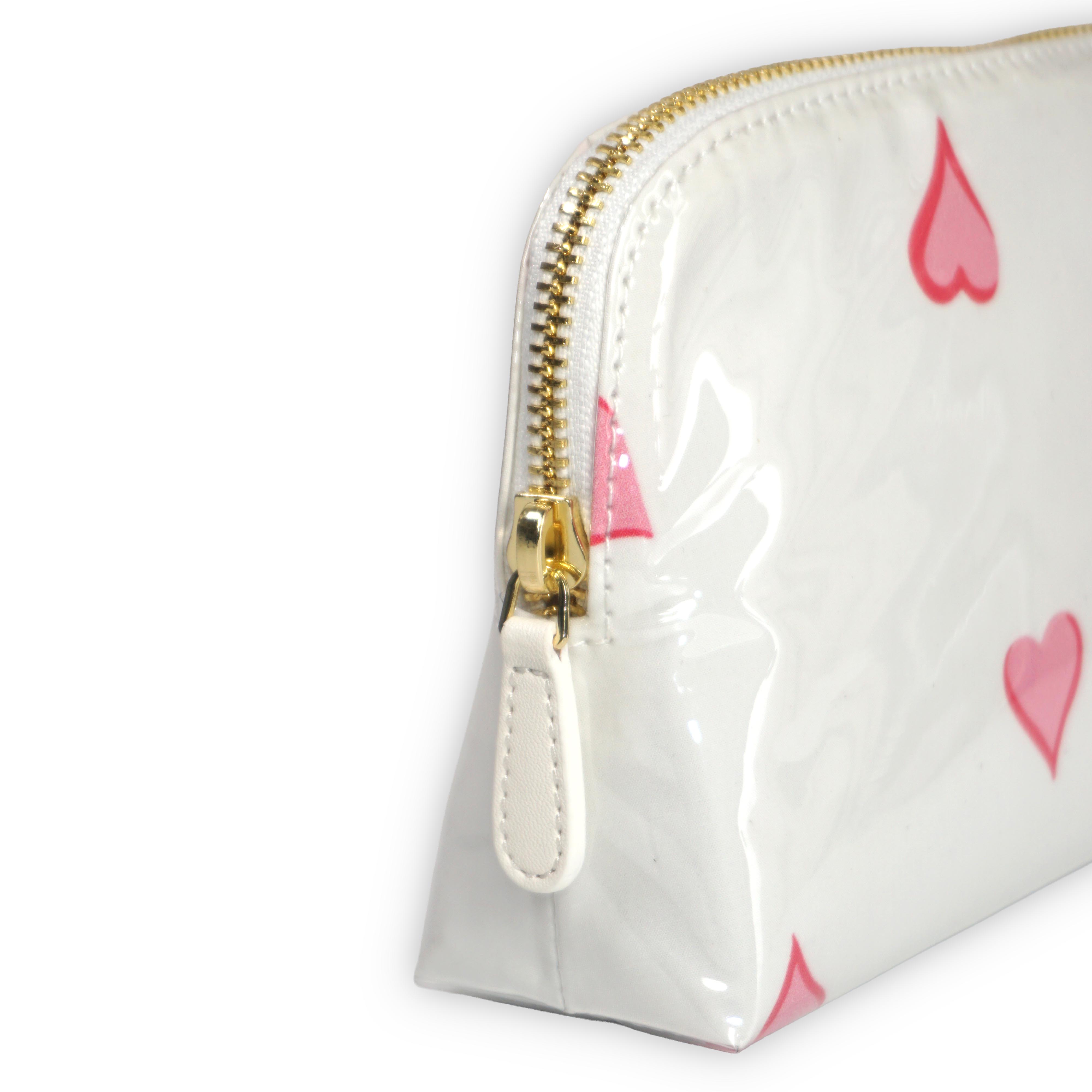 Small white cosmetic pouch featuring scattered pink heart motifs, finished with a gold-tone brass zip closure.