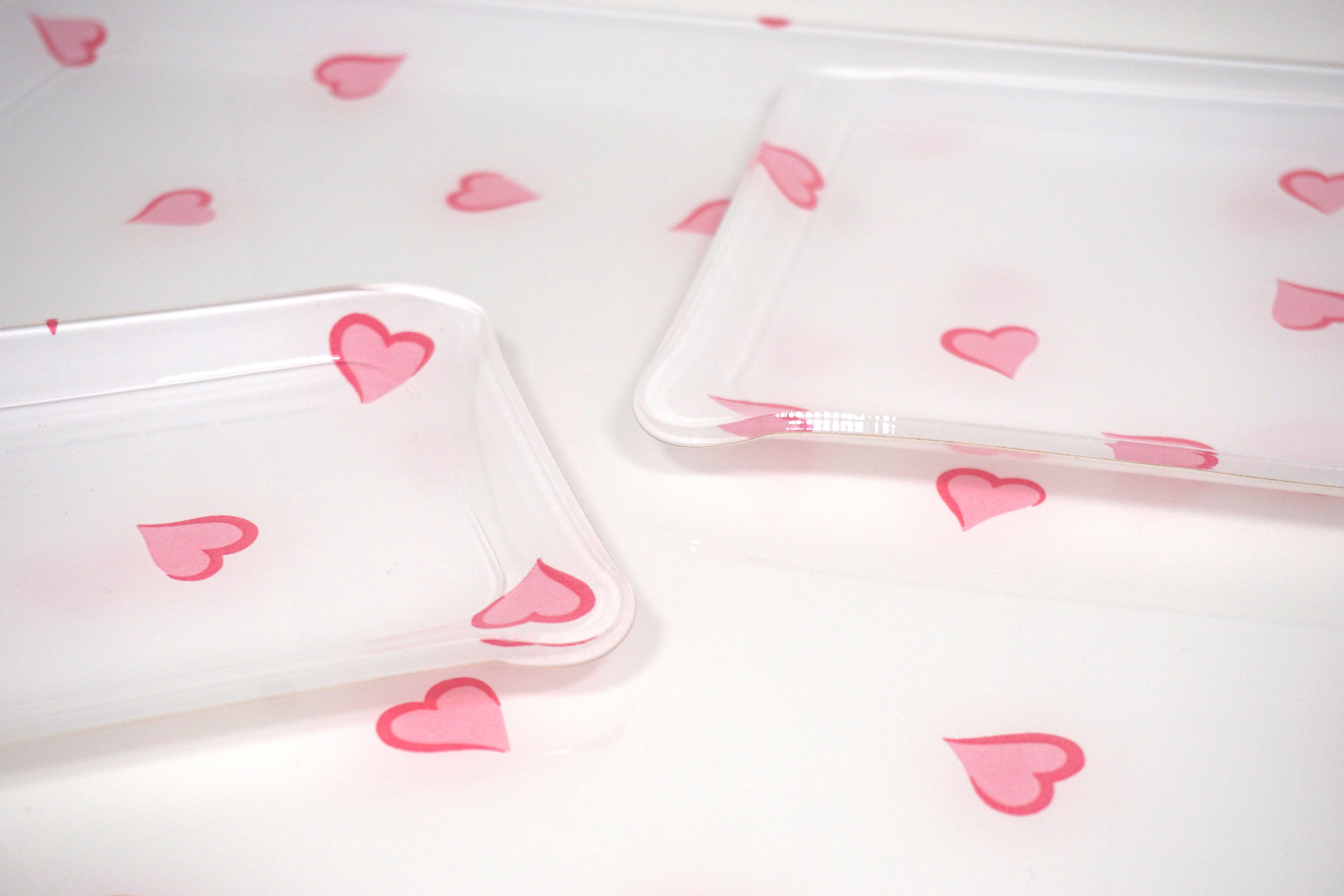 Printed Laminated Trays, side view of small and medium size trays on top of large tray. Each tray in scattered pink hearts, Coeurs print.