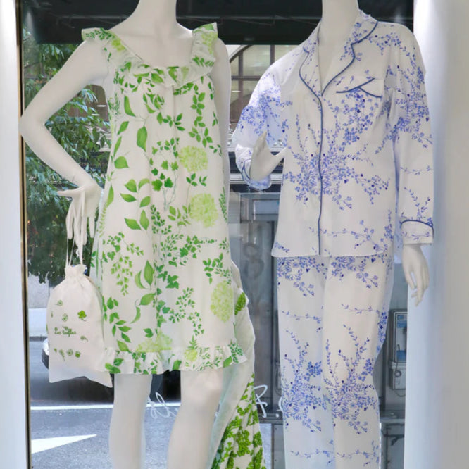 Mannequins wearing floral outfits in a display case with a light blue background.