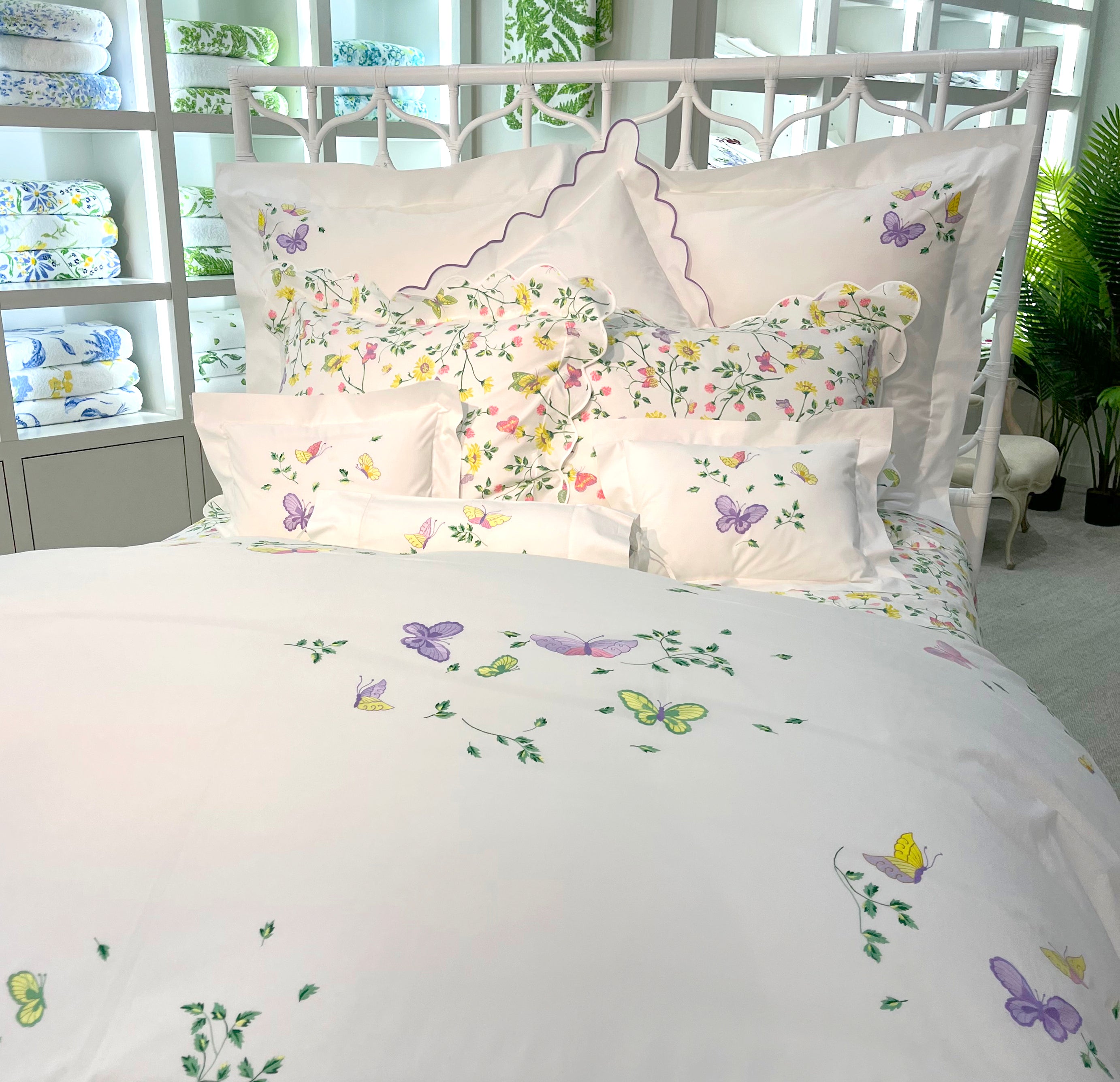 Printed and embroidered florals and butterflies (in pink, yellow, lilac and green) bed linens displayed on bed.