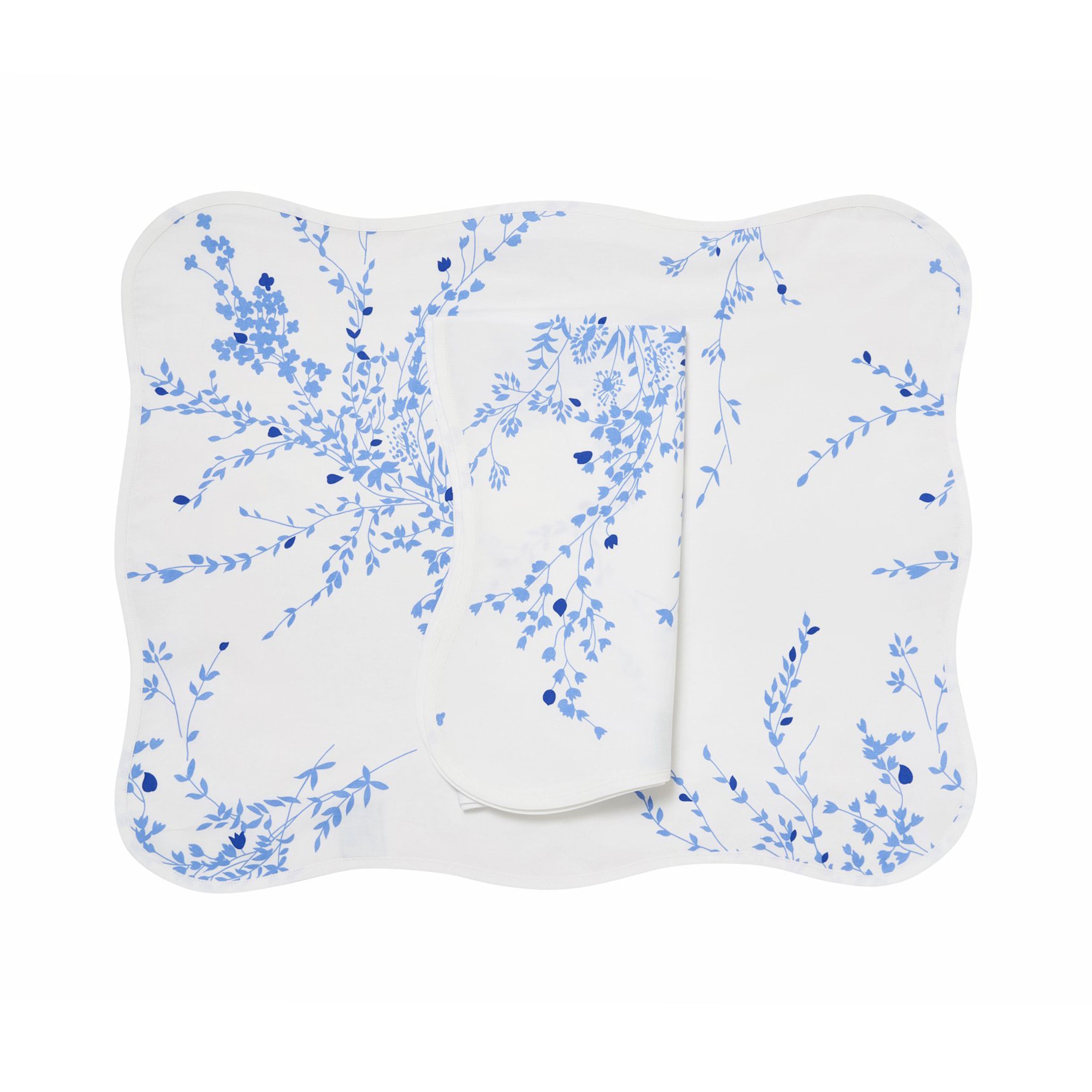Blue florals, Jete de Fleurs print, shown on placemat with a folded napkin, finished with a wavy white bias, on a white background.