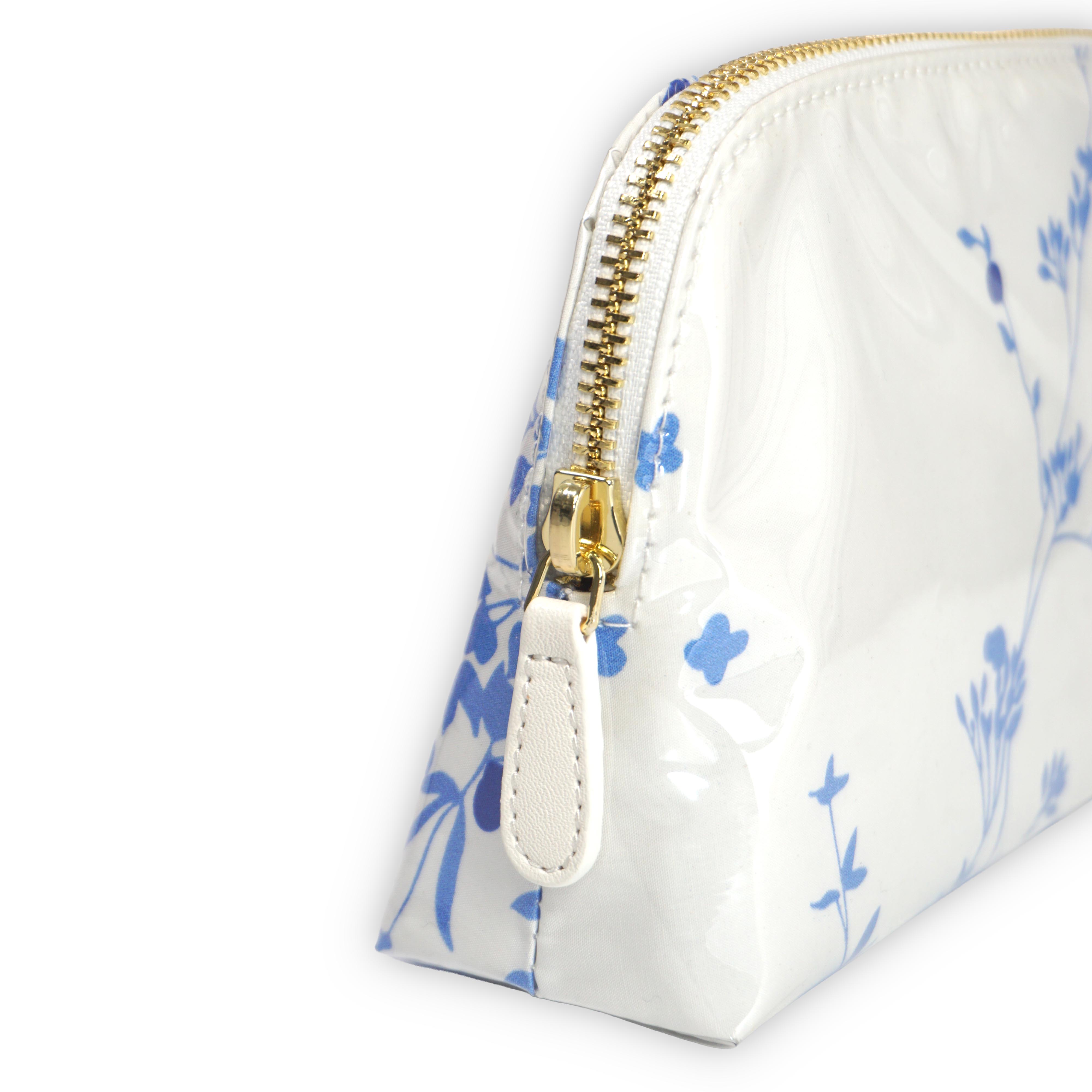 Small white cosmetic pouch featuring blue floral motifs in Jete de Fleurs, finished with a gold-tone brass zip closure.