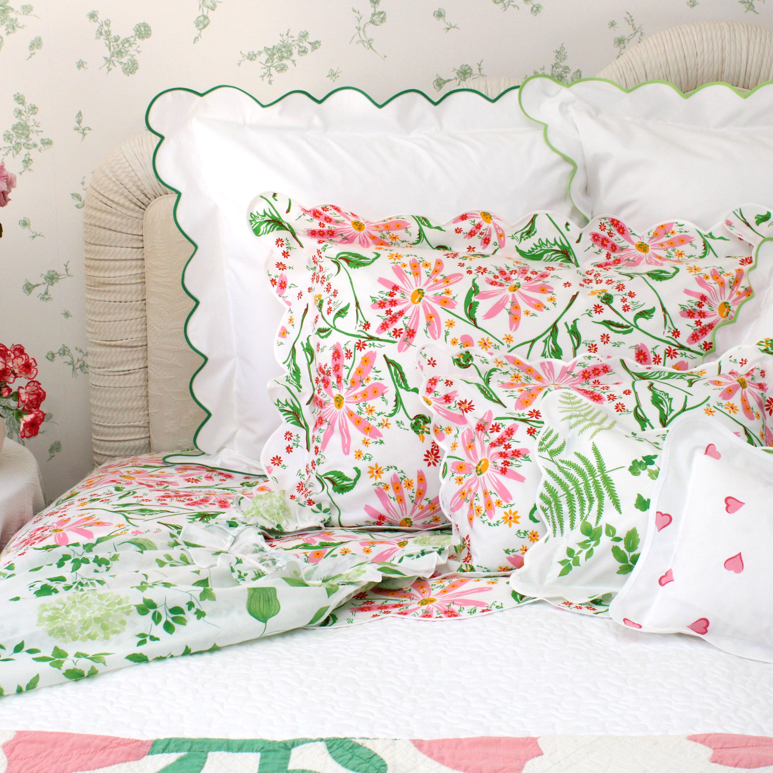 Floral bedding set with pink and green flowers on a bed with white pillows.