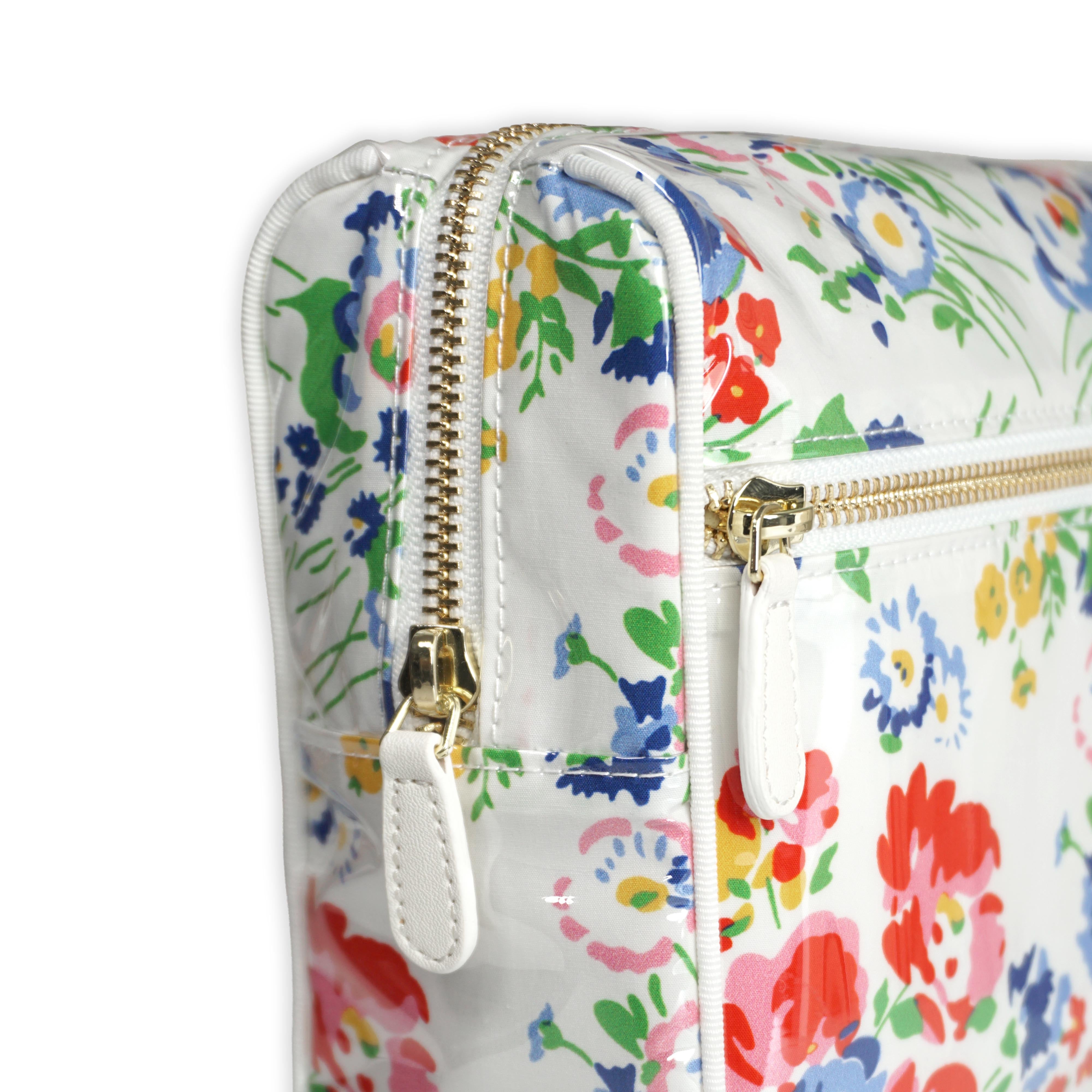 Large cosmetic bag featuring multicolored floral motifs in New York Mille Fleurs, with a brass zip closure along the top and an exterior front zip pocket.
