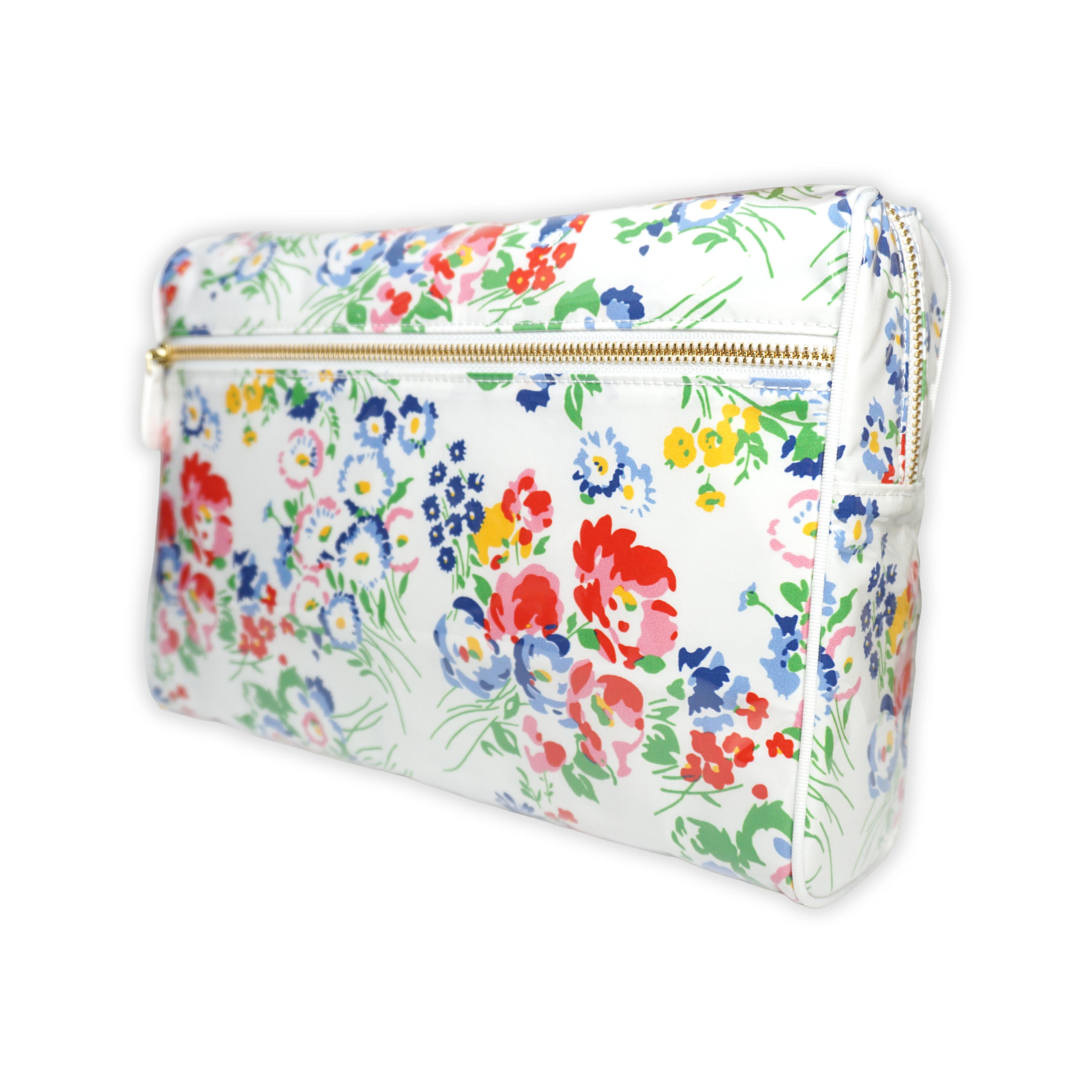Large cosmetic bag featuring multicolored floral motifs in New York Mille Fleurs, with a brass zip closure along the top and an exterior front zip pocket.