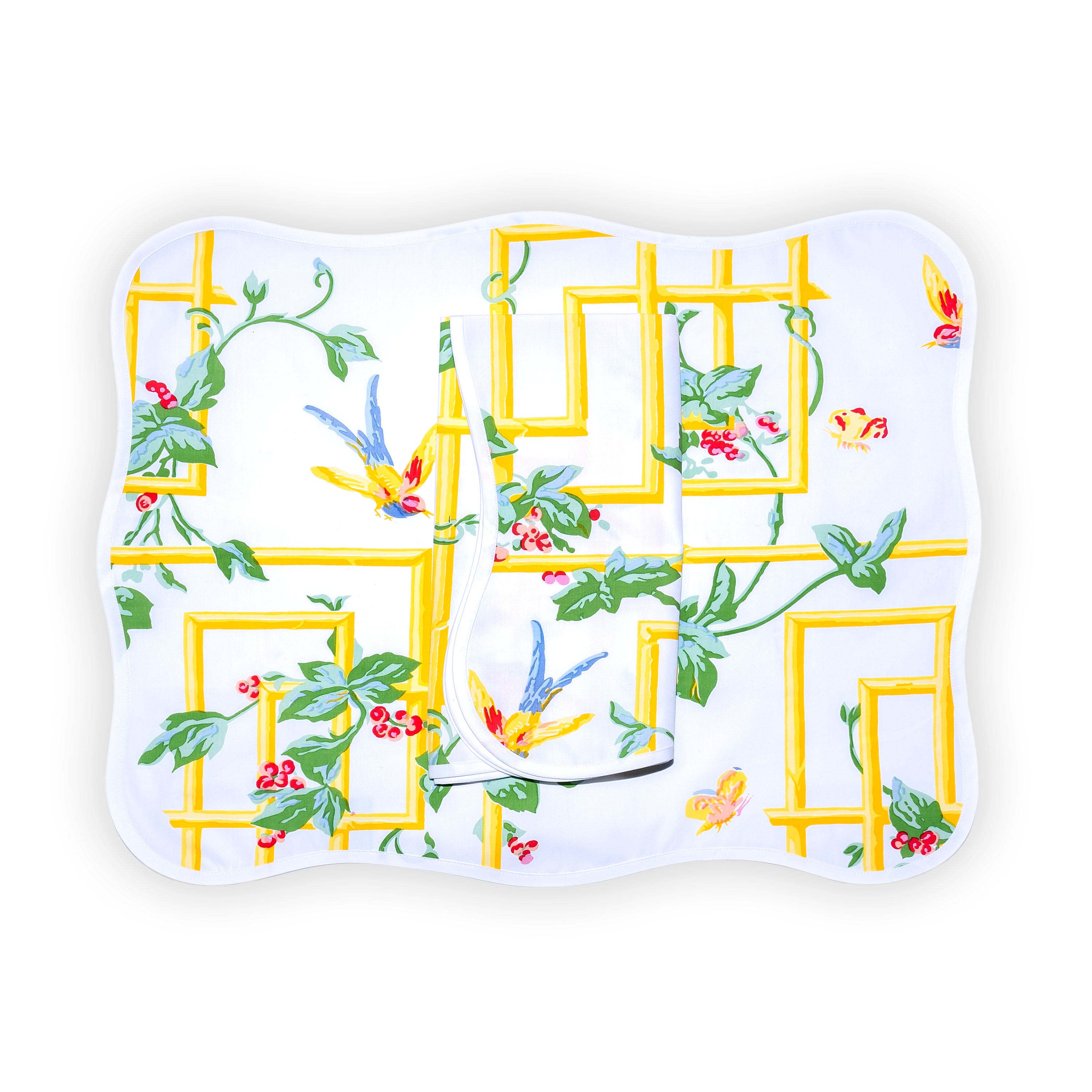 Yellow pergola motif accented with green leaves/vines, red berries, colorful small butterflies and birds, Pergola print, shown on placemat with a folded napkin, finished with a wavy white bias, on a white background.