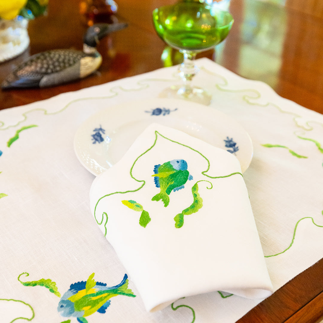 Embroidered tablecloth with fish design on a wooden table
