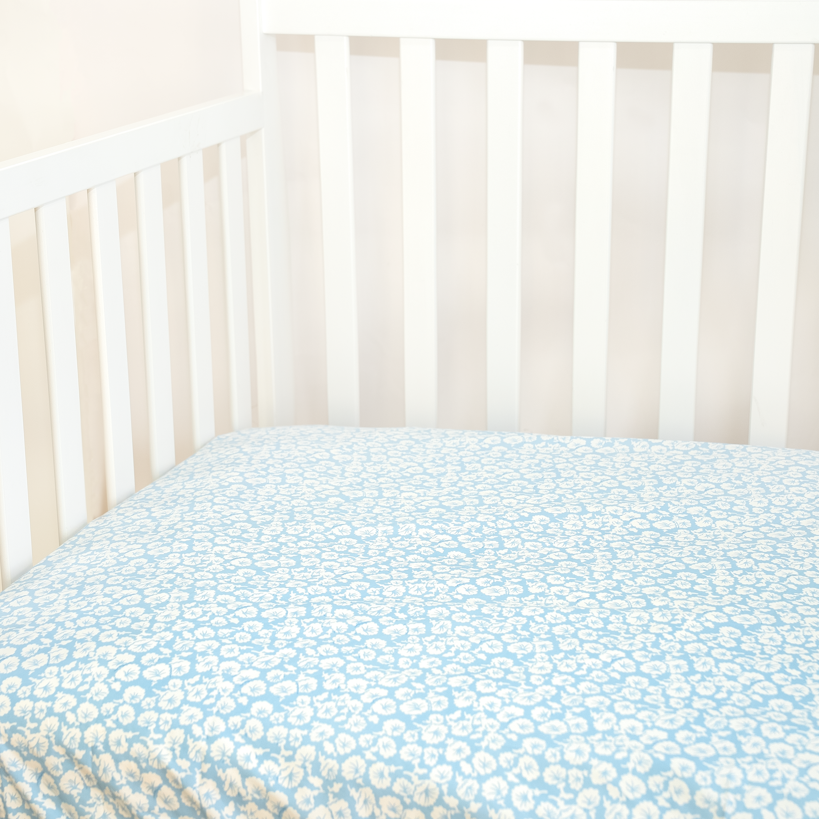 white floral pattern on baby blue background fitted sheet in crib