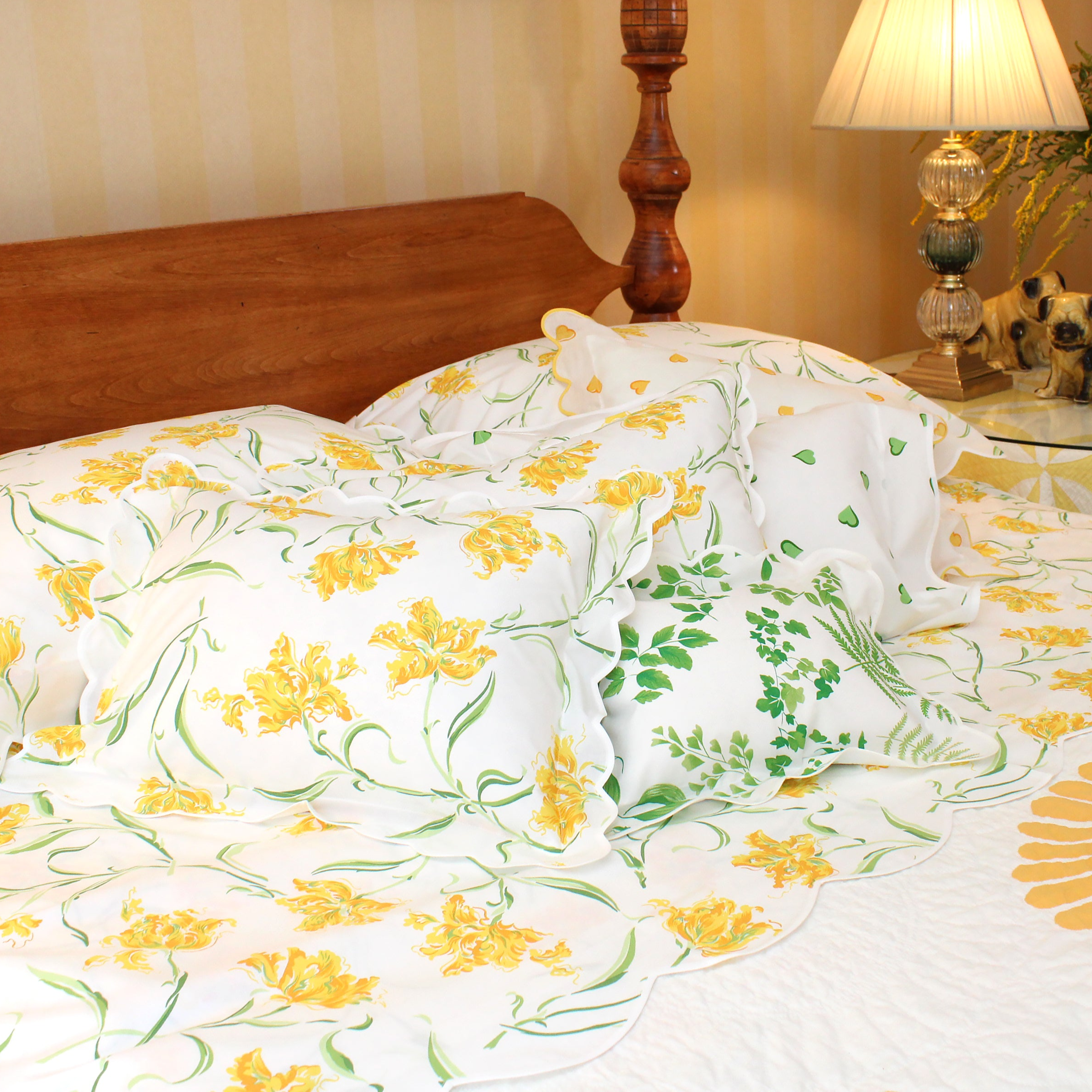 Floral-patterned bedspread on a bed with wooden headboard and lamp in the background.