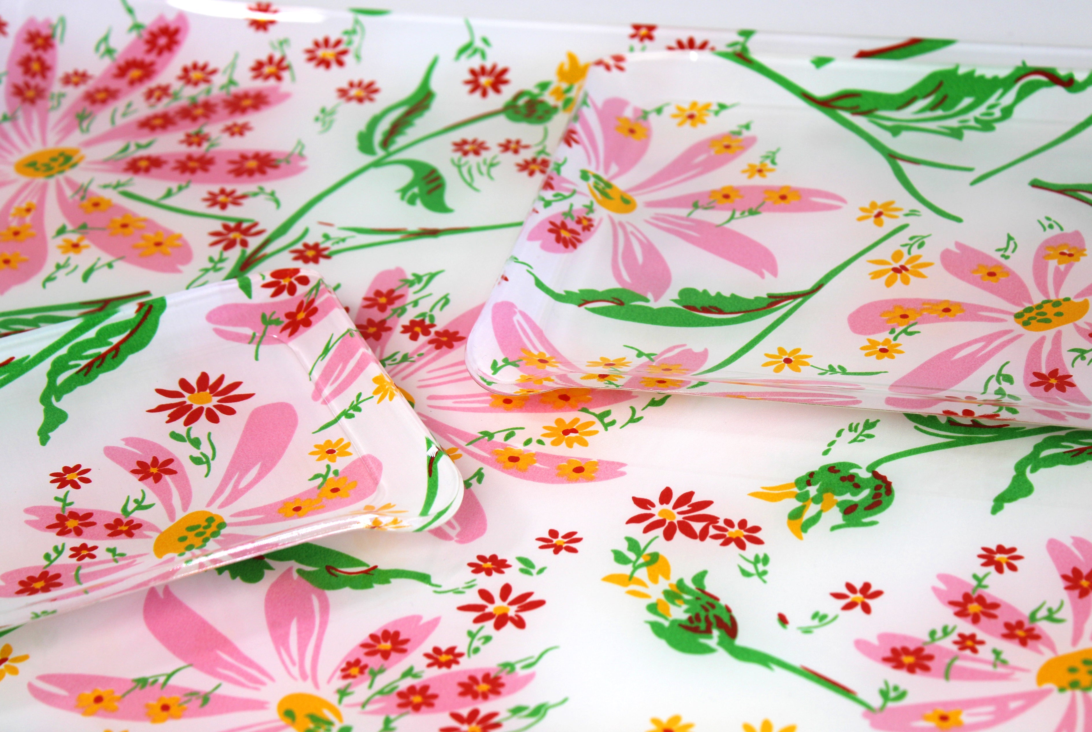 Printed Laminated Trays, side view of small and medium size trays on top of large tray. Each tray in pink, yellow and red florals with green leaves/stems, Marguerites Pink print.