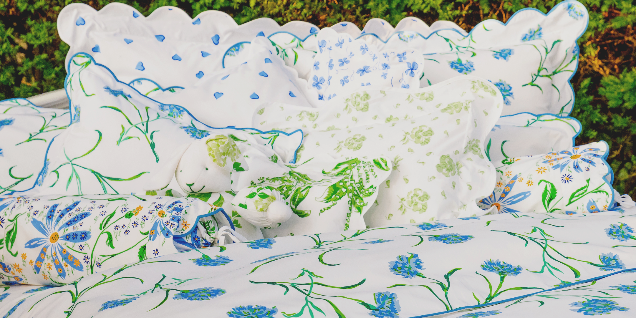 Floral-patterned cushions on a bed with a green outdoor background