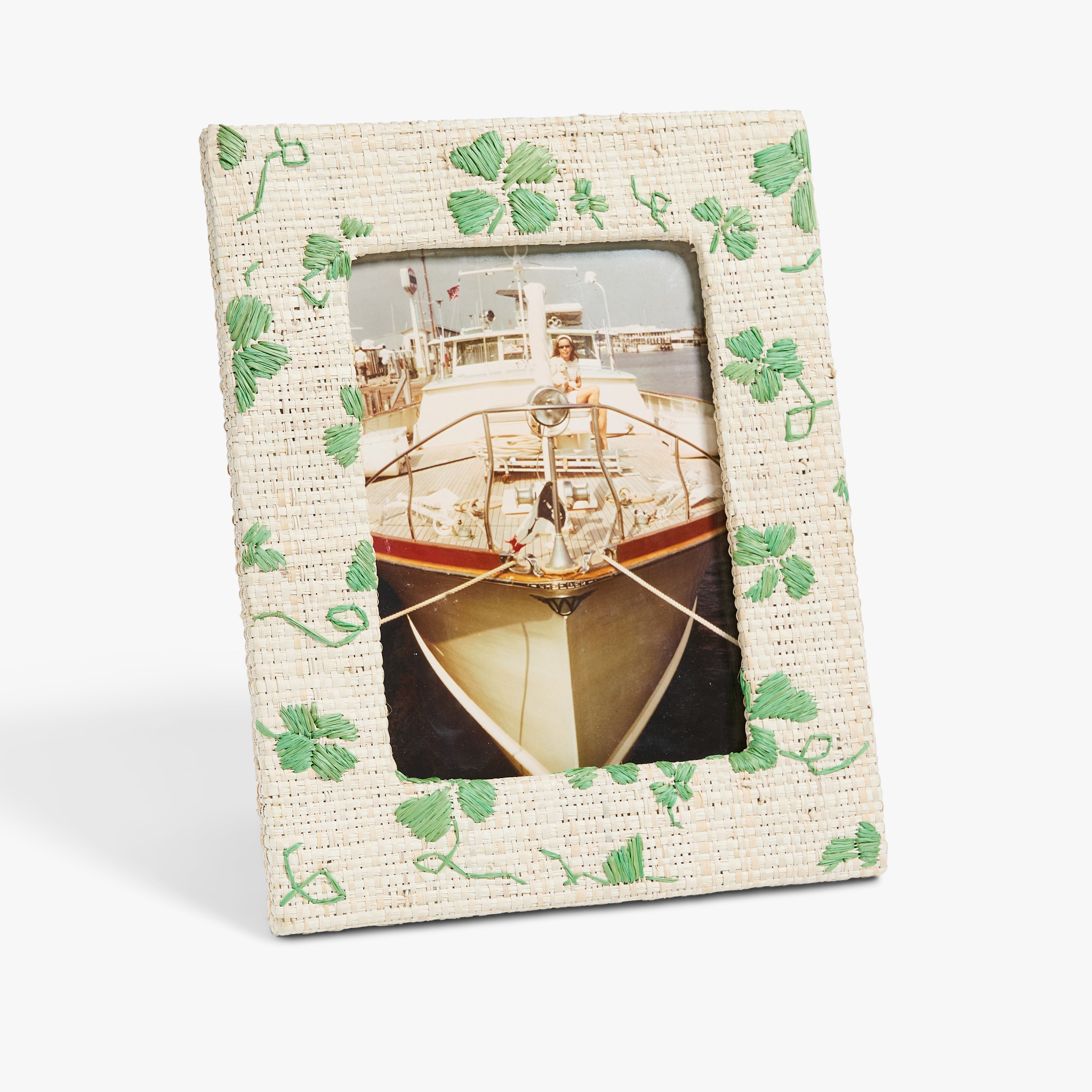 A photo in a textured frame with green clover embroidery shows a boat with a person on deck.
