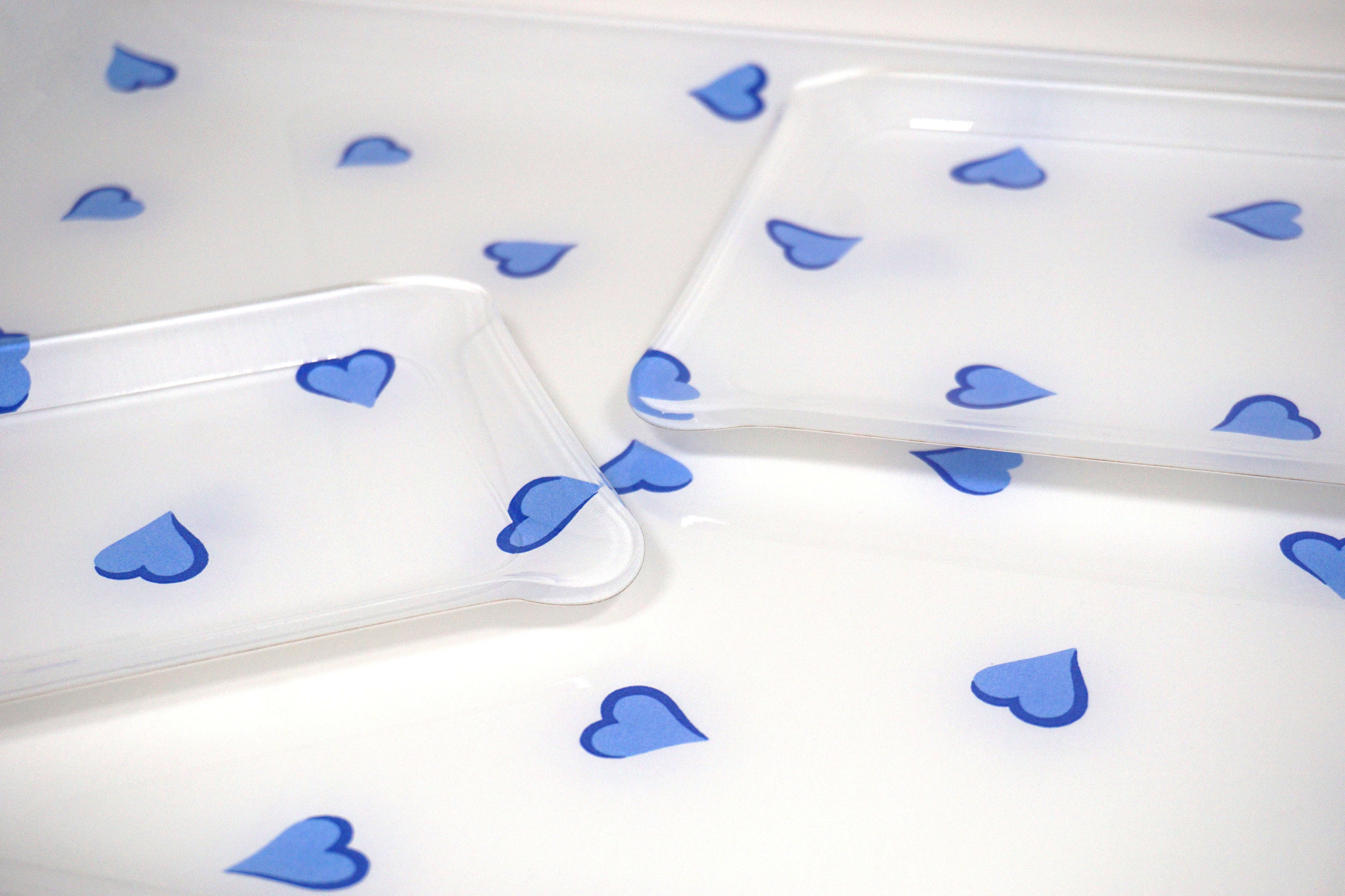 Printed Laminated Trays, side view of small and medium size trays on top of large tray. Each tray in scattered blue hearts, Coeurs print.