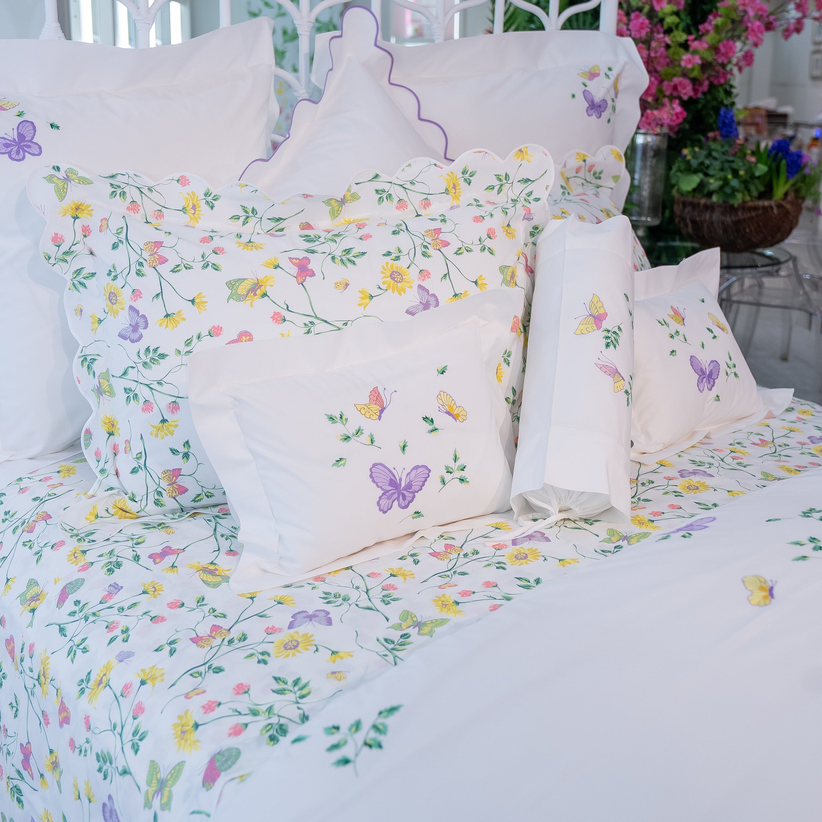 Printed and embroidered florals and butterflies (in pink, yellow, lilac and green) bed linens displayed on bed.