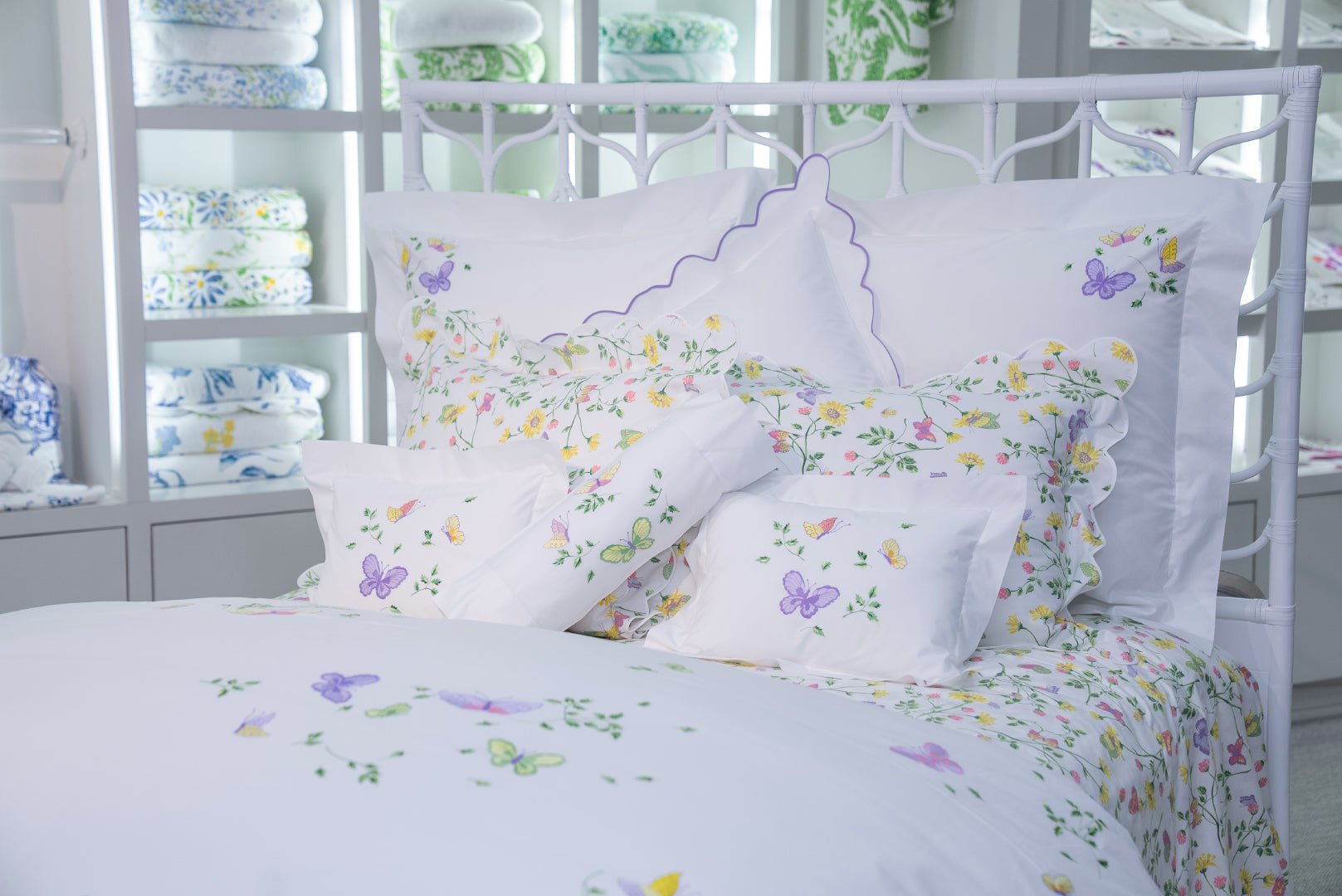 Printed and embroidered florals and butterflies (in pink, yellow, lilac and green) bed linens displayed on bed.