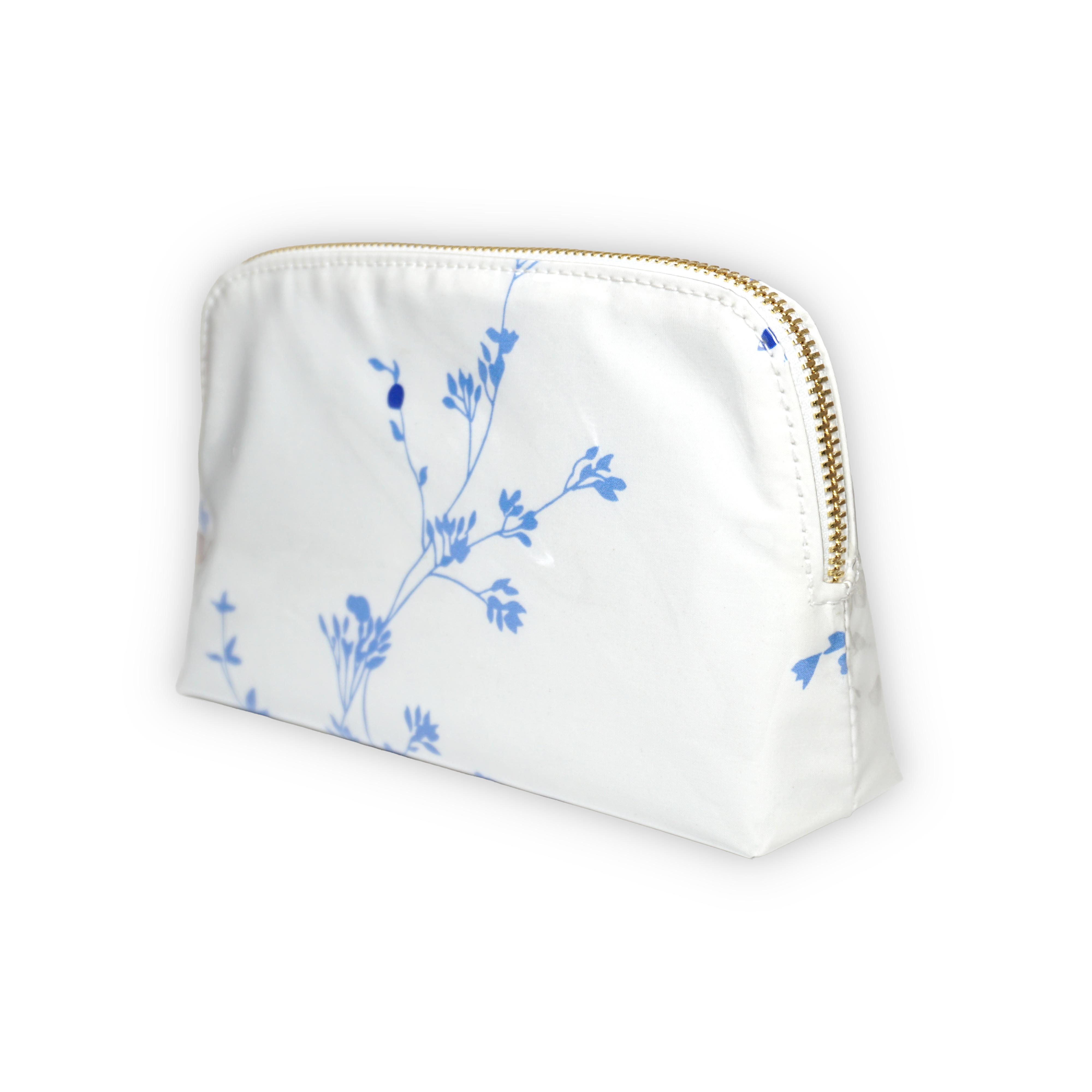 Small white cosmetic pouch featuring blue floral motifs in Jete de Fleurs, finished with a gold-tone brass zip closure.