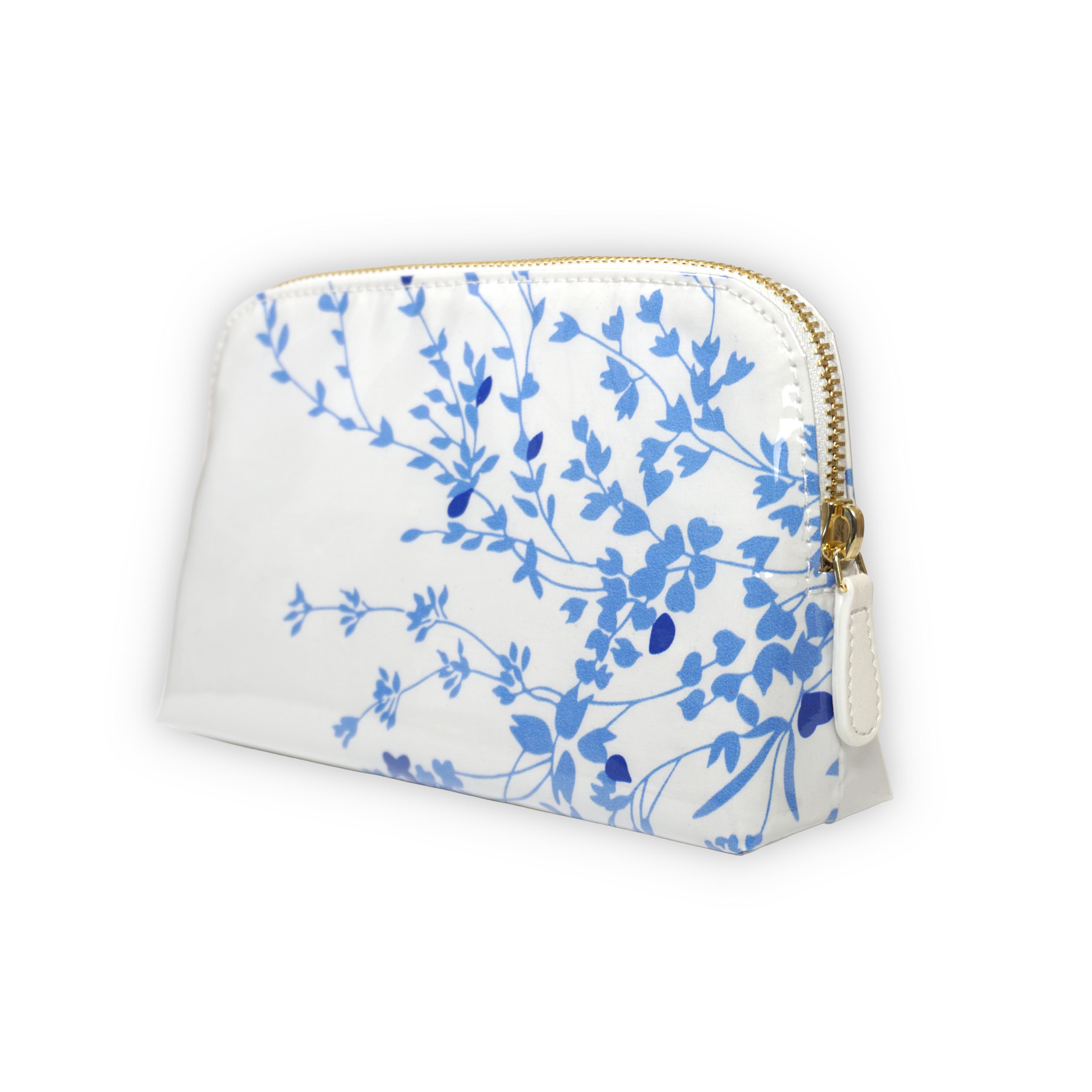 Small white cosmetic pouch featuring blue floral motifs in Jete de Fleurs, finished with a gold-tone brass zip closure.
