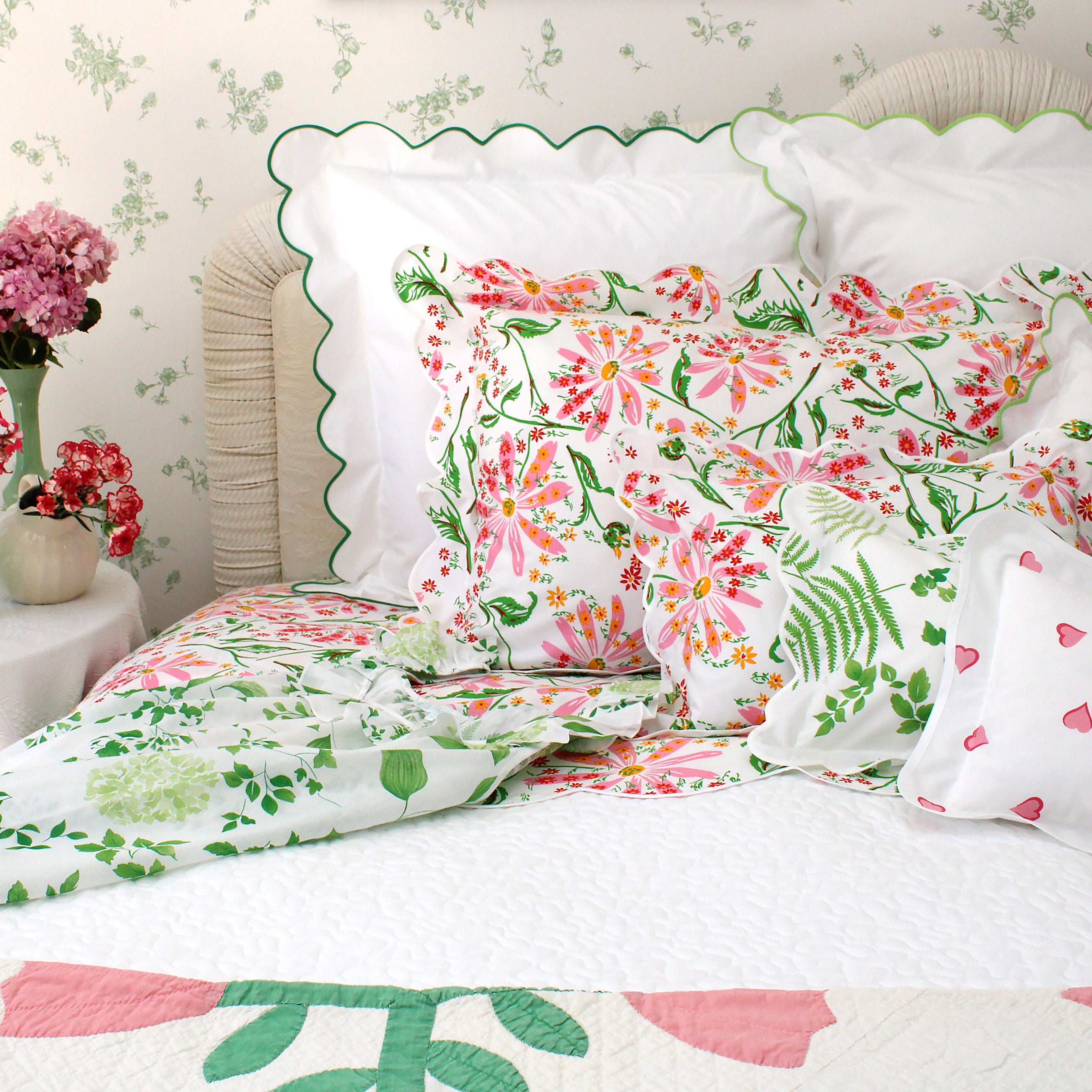 Floral bedding set with pink and green flowers on a bed with white pillows.