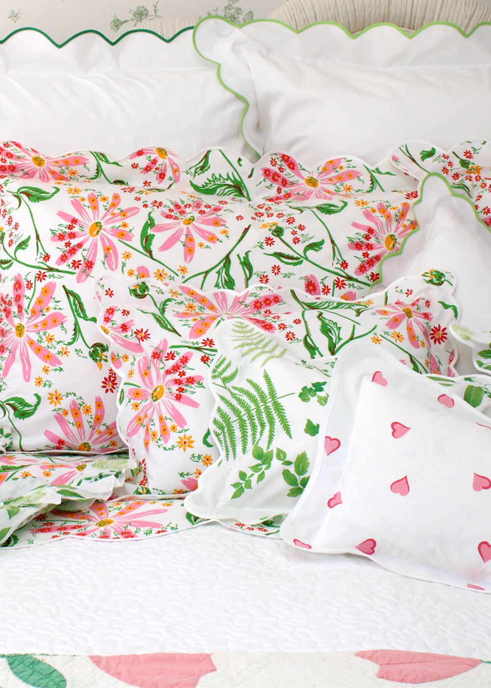 Floral bedding set with pink and green flowers on a bed with white pillows.