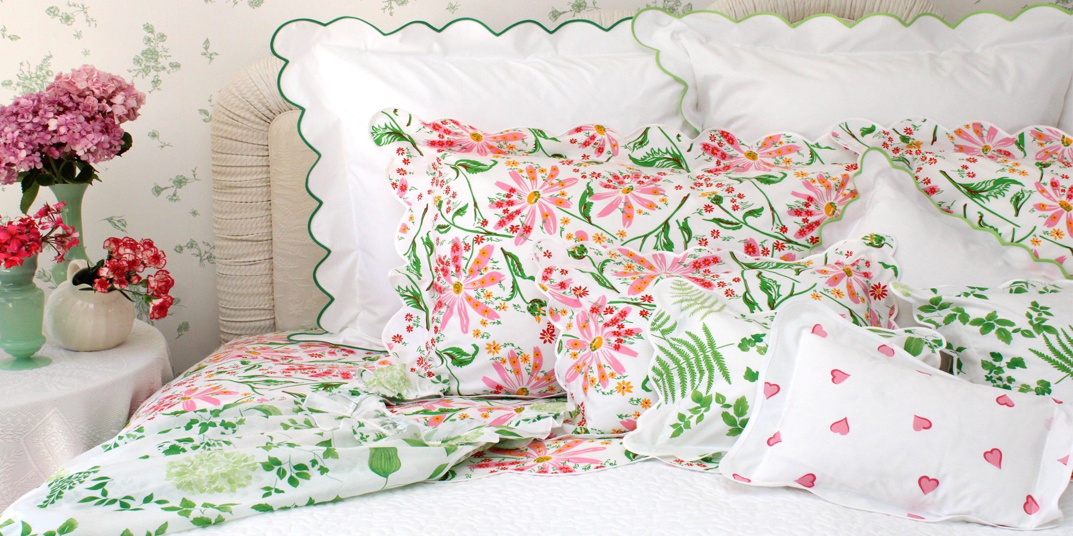 Floral bedding set with pink and green flowers on a bed with white pillows.