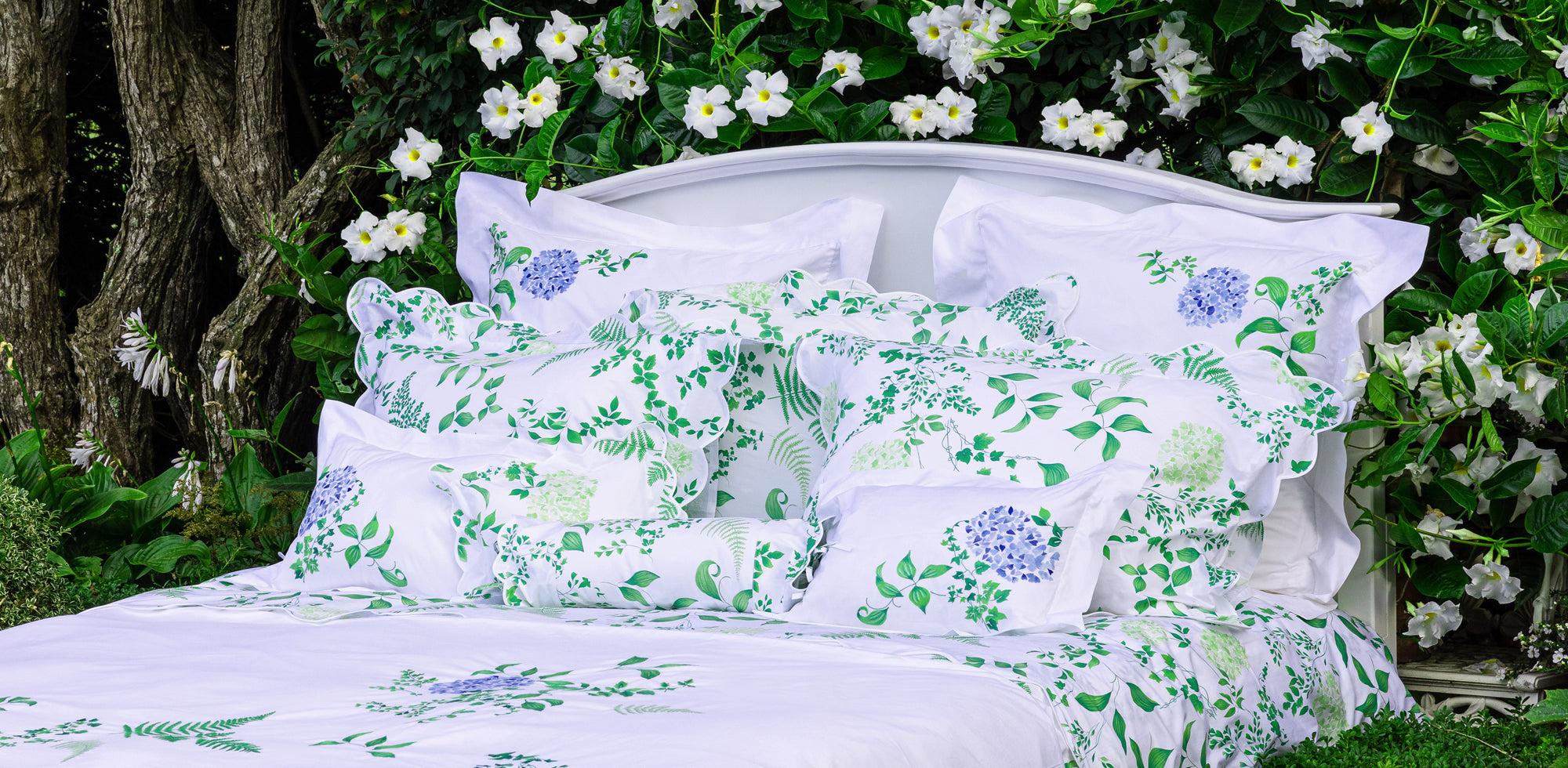 Floral-patterned bedding set in a garden setting with white flowers and greenery.