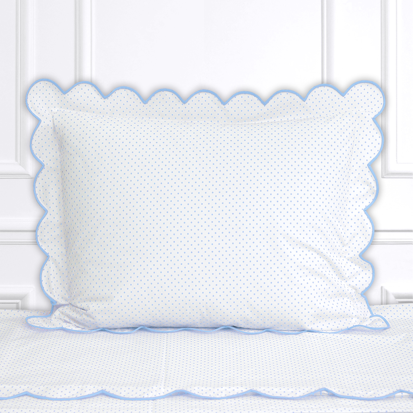Blue polka dots, Mini Confettis print shown on a Standard Sham with a scallop blue bias, on top of matching bed sheet with a white panel background.