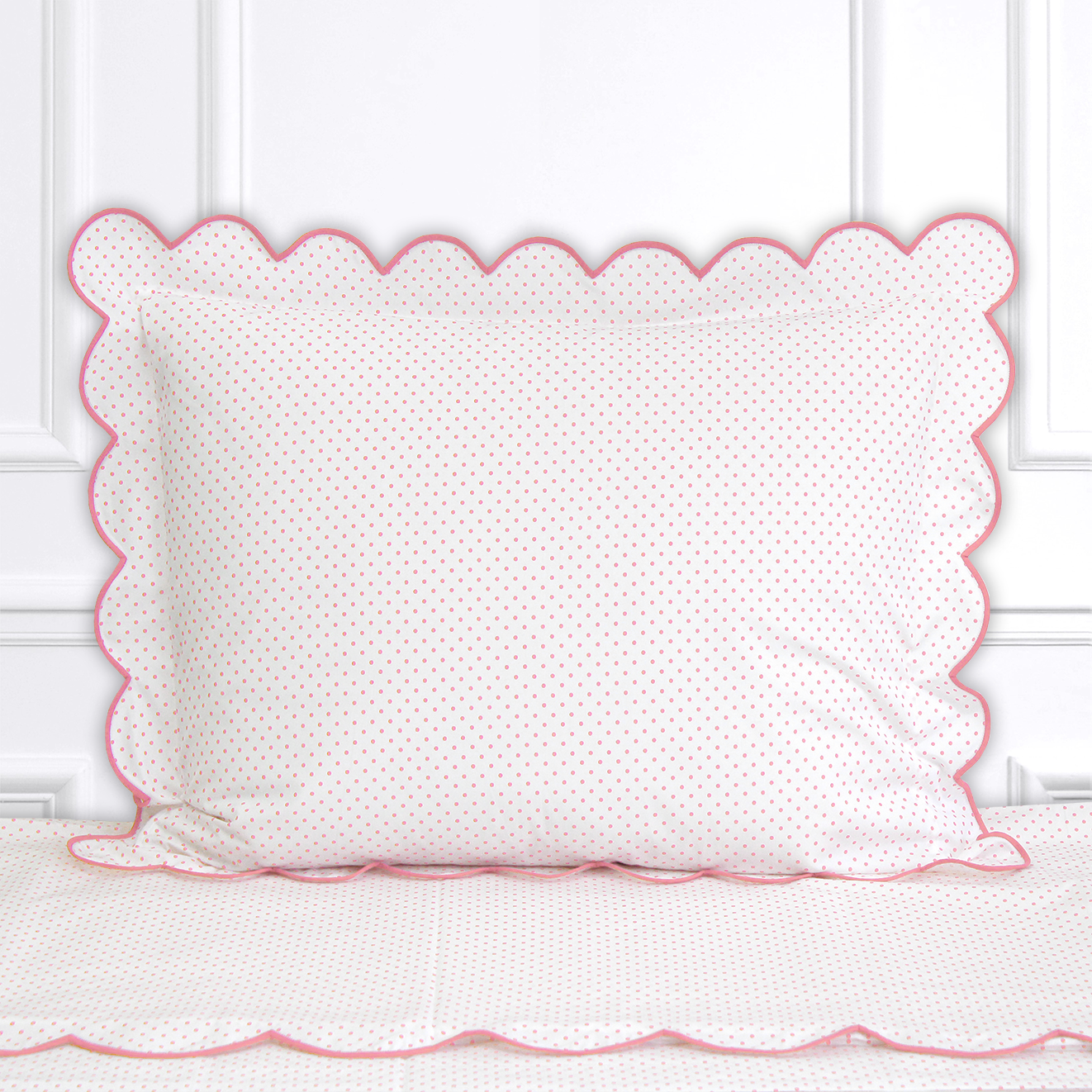 Pink polka dots, Mini Confettis print shown on a Standard Sham with a scallop pink bias, on top of matching bed sheet with a white panel background.