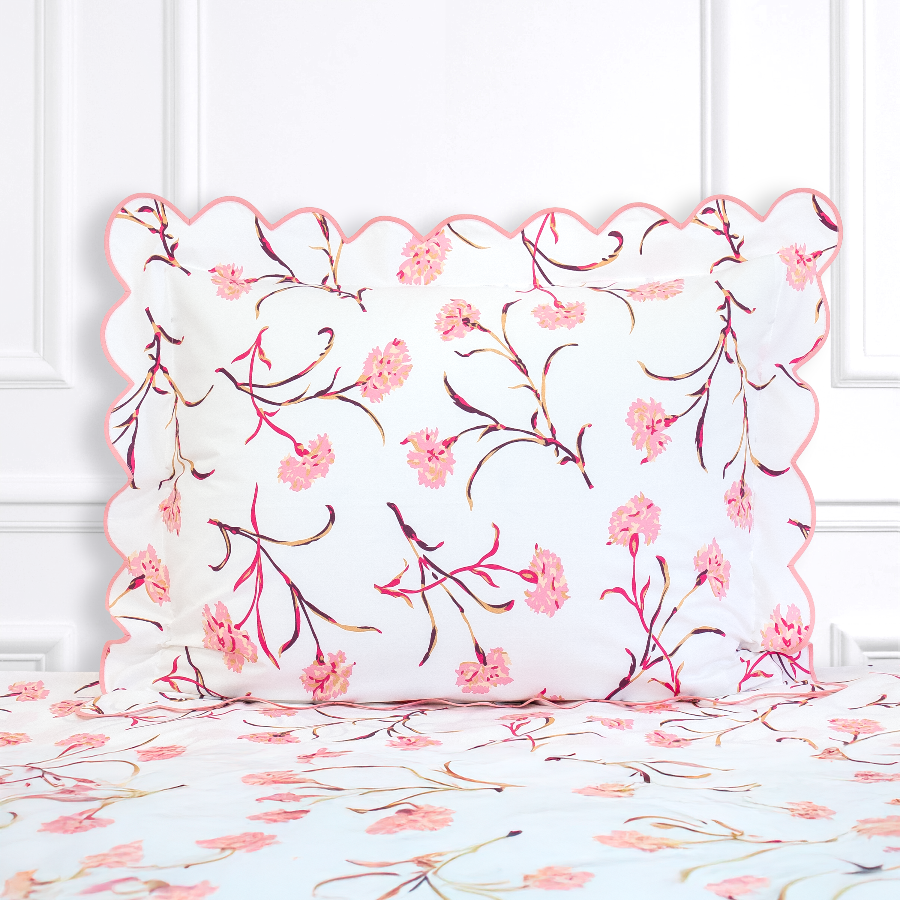 Pink and Burgundy color floral, Carnations print shown on a Standard Sham with a scallop blue bias, on top of matching bed sheet with a white panel background.