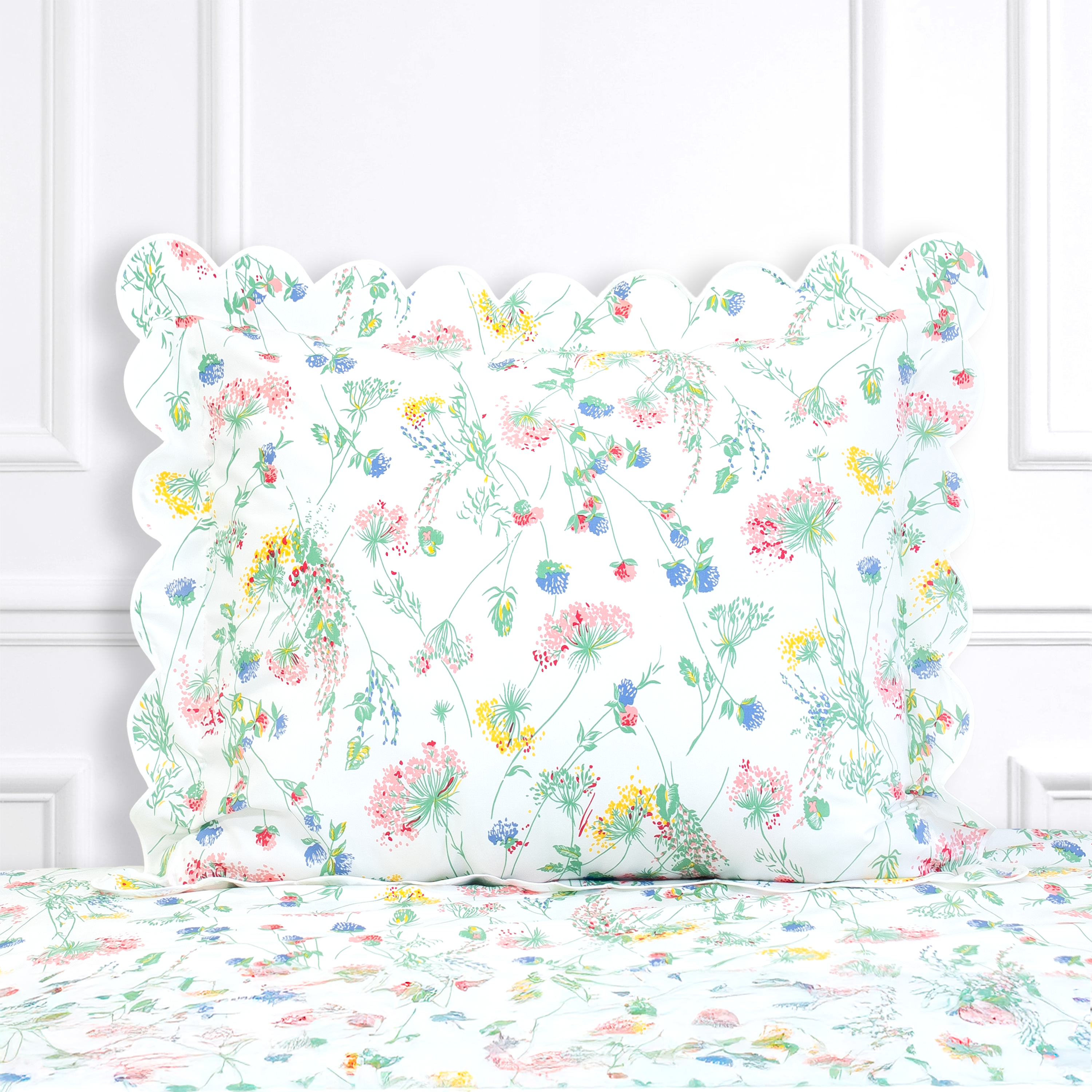 Multi color floral, Chardons Luzerne print shown on a Standard Sham with a scallop white bias, on top of matching bed sheet with a white panel background.