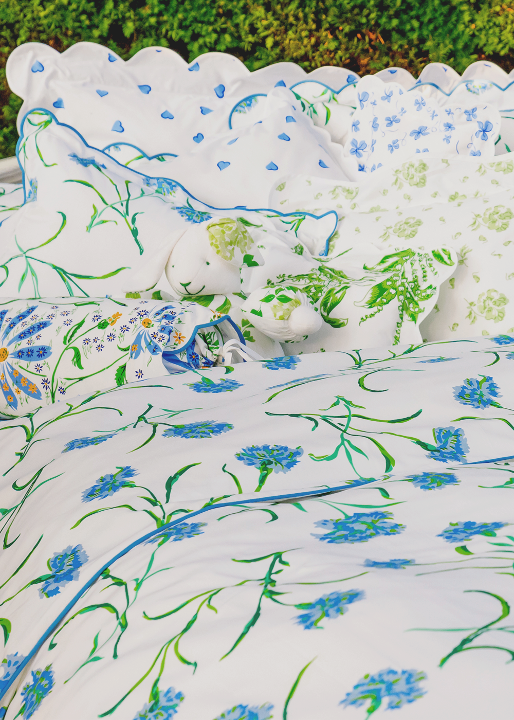 Floral-patterned cushions on a bed with a green outdoor background