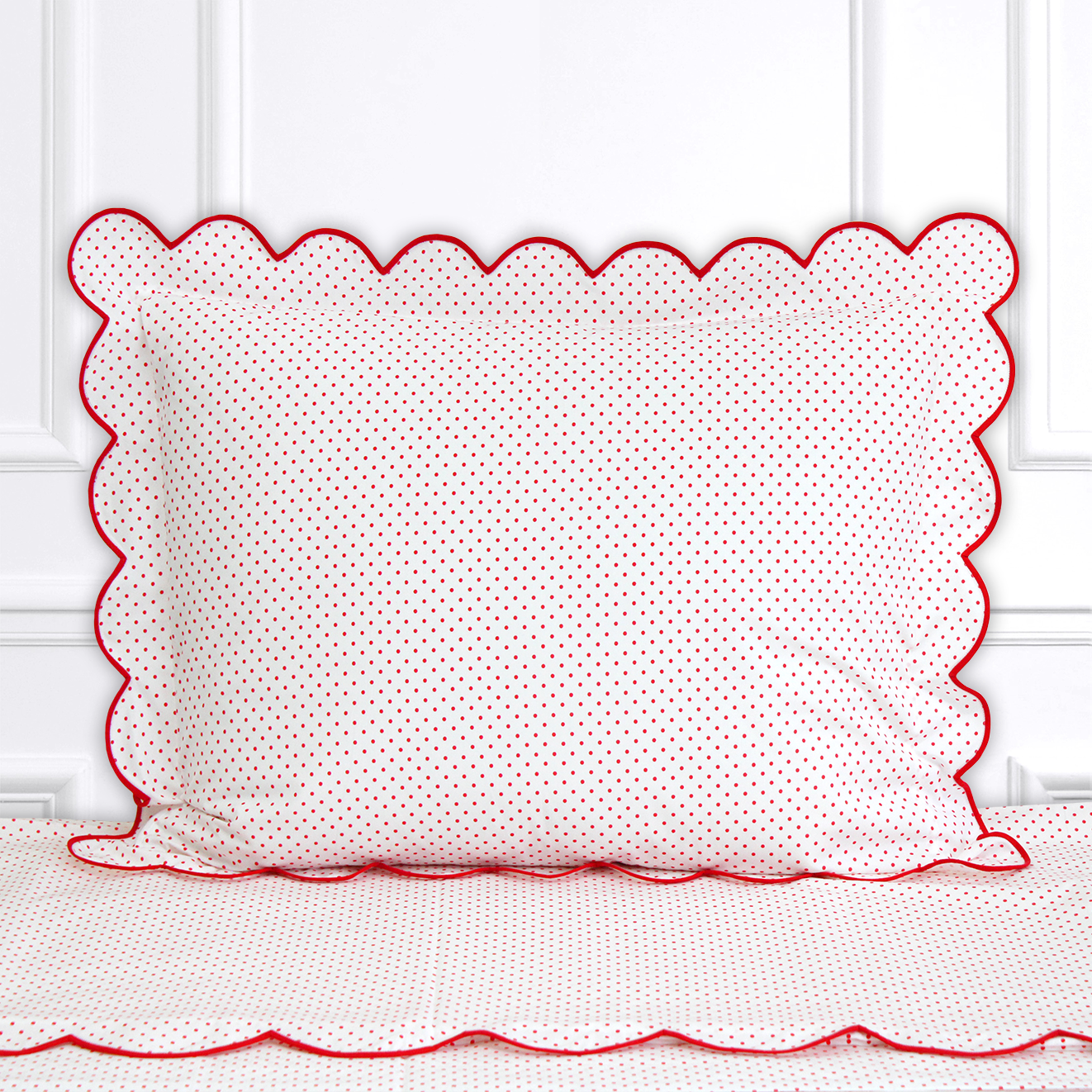 Red polka dots, Mini Confettis print shown on a Standard Sham with a scallop red bias, on top of matching bed sheet with a white panel background.